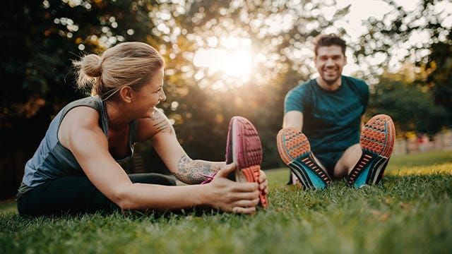 Man en vrouw doen rekoefeningen in het park